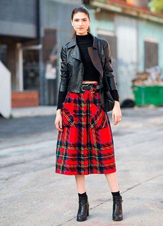 Look com jaqueta de couro e saia xadrez.